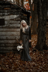 Fototapeta premium Witch in a long black dress walking through the village in the dark