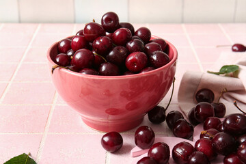 Bowl with sweet cherries on pink tile background