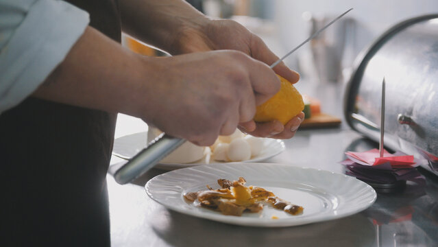 Chef is peeling potatoes for salad in commercial kitchen, close-up view