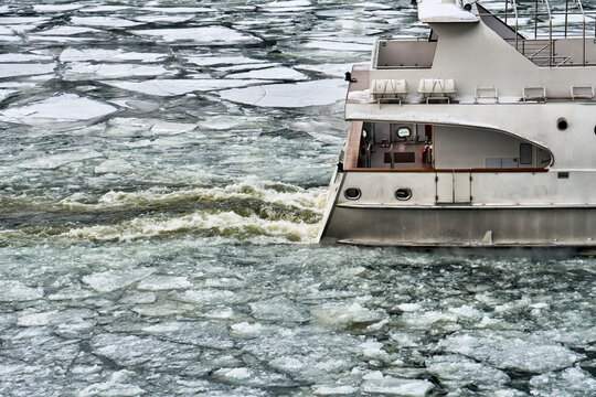 Stern of ship sailing along a river covered with a broken ice in early spring