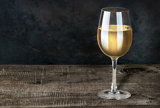 Glass of white wine on a wooden table. Dark background. Wooden table of plates.