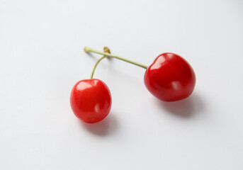 Obraz na płótnie Canvas two berries of red juicy delicious cherries on a white table.selective focus . High quality photo