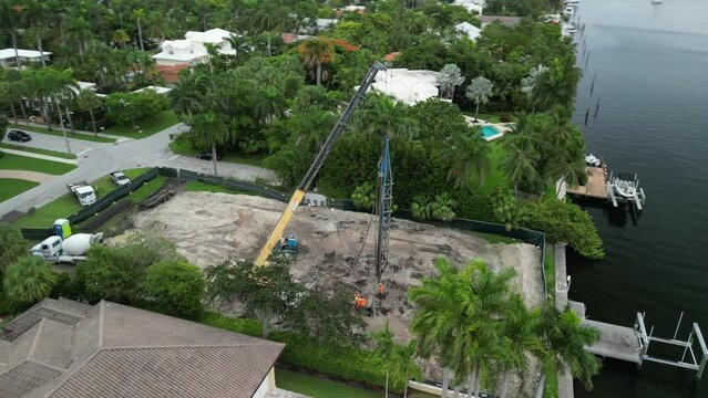 Aerial view circling a construction crane at a waterfront home construction site