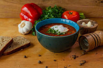 Bowl of borscht with garlic and bread on wooden table