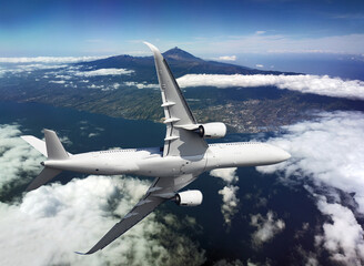 Fototapeta premium Airplane flying over the island and mountains with a clouds
