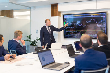 Business man making a presentation at office. Business executive delivering a presentation to his colleagues during meeting or in-house business training, explaining business plans to his employees.