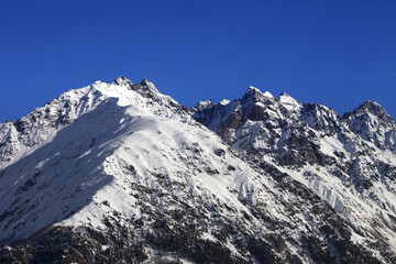 Snowy rocks and blue clear sky at nice winter day. Caucasus Mountains. Svaneti region of Georgia.