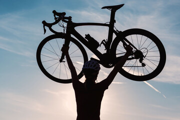 Cyclist on a racing bike outdoors in nature at sunset.