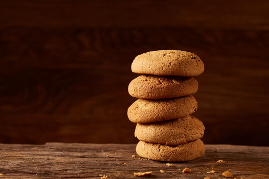 Pile of oat cookies on wooden table, close-up, selective focus. Crunchy stack. Delicious snack. Homade bakery. Tasty biscuit. Nutritious sweet food on rustic background. Healthy food concept.
