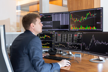 Fototapeta na wymiar Businessman trading stocks. Stock traders looking at graphs, indexes, numbers and analyses on multiple computer screens in modern trading office.