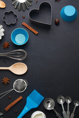 Baking background with eggs and kitchen tools: rolling pin, wooden spoons, whisk, sieve, bakeware and shape cookie  cutter on dark wooden background. Vertical orientation with copyspace, top view.