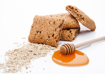 Healthy bio breakfast grain biscuits with honey and raw oat porridge on white background
