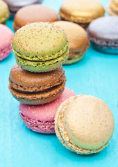 French luxury colorful macarons dessert cakes on blue wood background with sugar on top