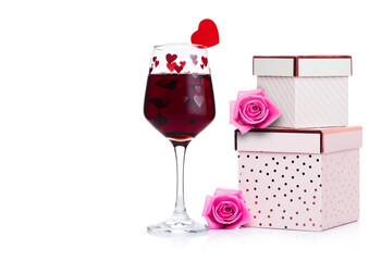Glass of red wine with heart and pink gift box and rose for valentine's day on white background