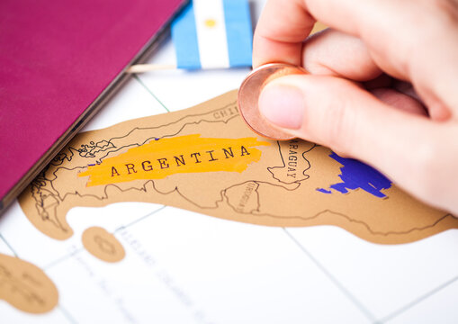 Travel holiday to Argentina concept with passport and flag with female hand choosing Argentina on the map