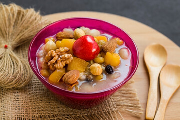 Traditional Turkish Dessert Asure,or Noah's Pudding in stylish pink color glass bowls on wooden plate