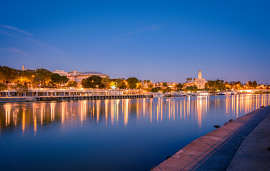 Cathedral, Giralda Tower and the Guadalquivir river in Sevilla, Spain. Blue hour view from Triana Quarter.