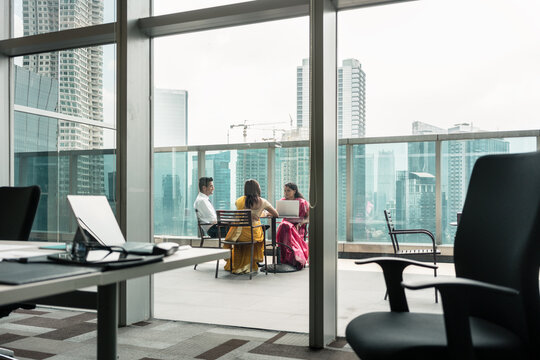 Three Indian employees during break on the terrace of a modern business building
