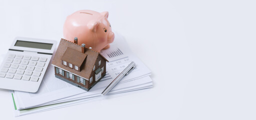 Model house, piggy bank, calculator and financial report on a desk: real estate, investments and home loan concept