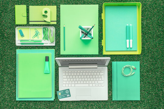 Green office supplies and laptop on the grass, business and ecology concept