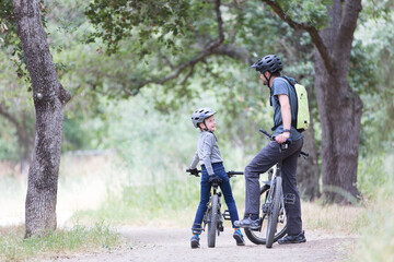 Naklejka premium family of two, young father and cheerful son, enjoying bike riding, active family concept