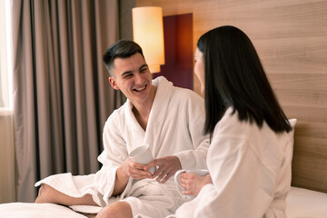 young couple on honeymoon in hotel room having breakfast in room drinking coffee happy lovers...