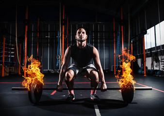 Determined athletic man works out at the gym with a fiery barbell