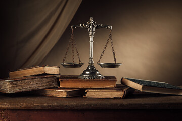 Old silver scale and hardcover books on a wooden table, justice and knowledge concept