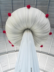Large white flower fabric which hanging from the metal roof of the flower exhibition hall.