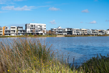 Caroline Springs Lake with some buildings of modern apartments  and luxury houses in the distance. Concept of urban living, property investment, real estate development or a livable neighbourhood.