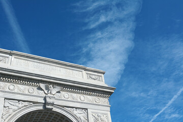 Detail of the marble arch in Washington Square Park, against a blue sky with light clouds