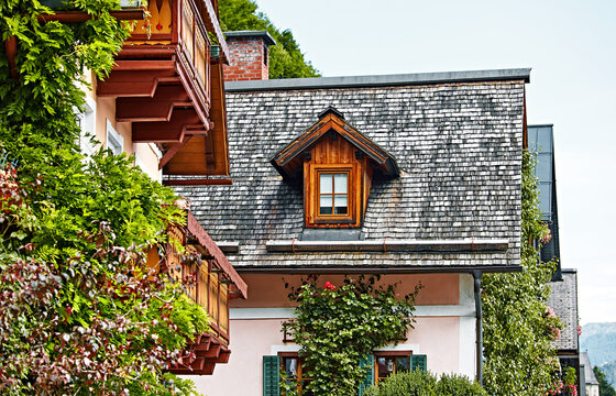 Hallstatt Austria. Houses with wooden balconies, windows and roofs. Racy antique traditional austrian houses among greenery, bushes and flowers.