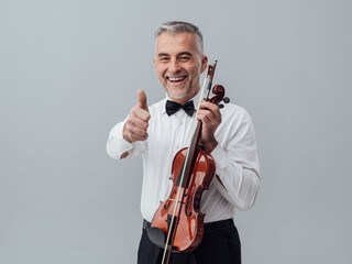 Cheerful violinist posing with a violin and giving a thumbs up