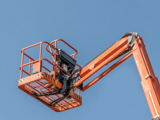 Single Orange Cherry Picker machinery against a blue sky