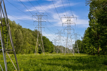 High-voltage power line in a forest clearing. Power transmission towers in the forest