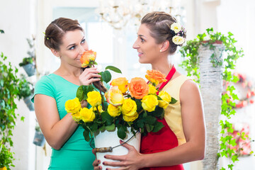 Fototapeta na wymiar Women in flower store enjoying the roses sniffing at them