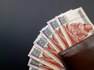 two hundred egyptian pounds with brown wallet isolated on black background - obrazy, fototapety, plakaty