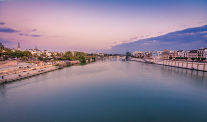 Obraz premium Blue Hour vew of Cathedral, Giralda Tower and the Guadalquivir river in Sevilla, Spain. View from Triana Bridge..