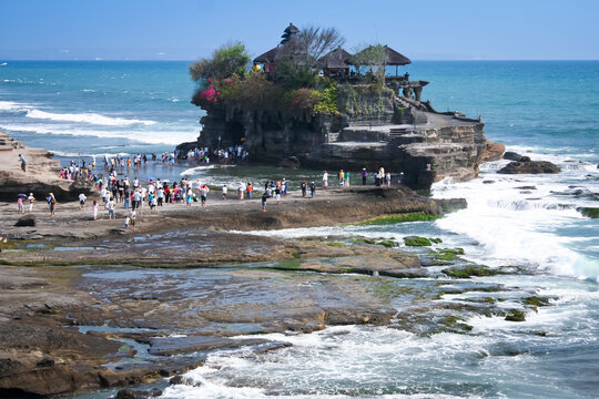 tourists crossing to the landmark sea temple of tanah lot on the coast of bali indonesia
