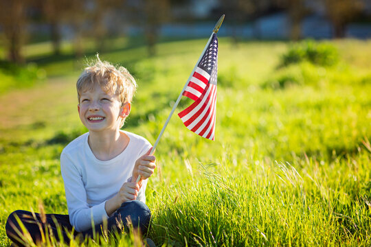 positive little boy with american flag celebrating 4th of july, independence day, or memorial day