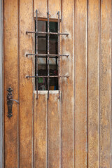 Rustic wooden door with rusty handle and security grille