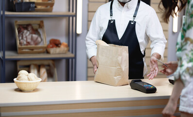 Small business concept senior female customer shopping bread and desserts at the local bakery professional baker serving his customer at his own bakery