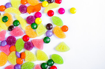Fototapeta na wymiar Scattered colored candy on a limited white background
