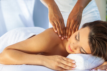 A young woman relaxing outside at a health spa while having a massage