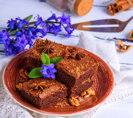 chocolate brownie pie in a ceramic brown plate on a white wooden table, top view