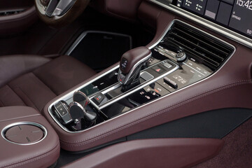Close-up on the control panel with a gear selector with touch buttons trimmed with wine color...
