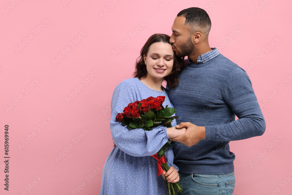 Wall mural Happy couple celebrating Valentine's day. Beloved woman with bouquet of roses on red background, space for text