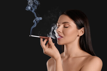 Obraz premium Woman using long cigarette holder for smoking on black background, space for text