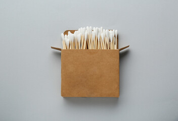 Cardboard box with cotton buds on light grey background, top view