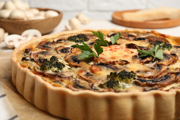 Delicious quiche with mushrooms and parsley on parchment paper, closeup